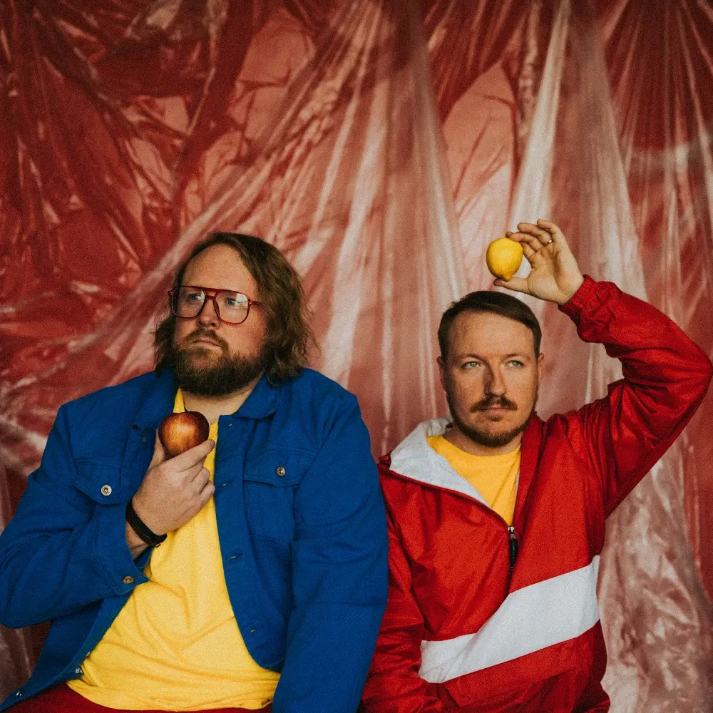 A photo of Nate and Klein holding lemons and apples above and around their heads.